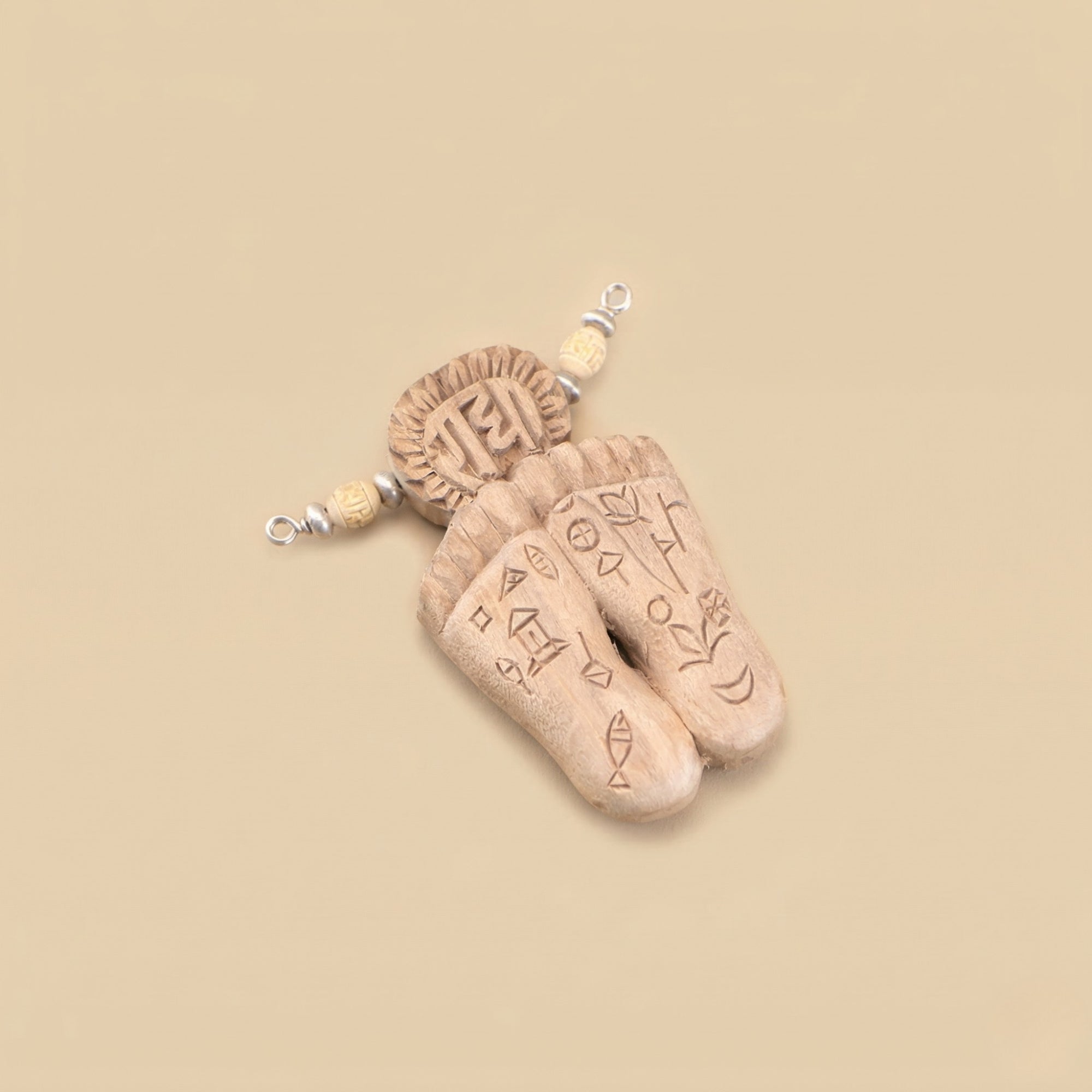 Close up flat lay of a silver pendant featuring authentic Tulsi wood carved with sacred lotus feet