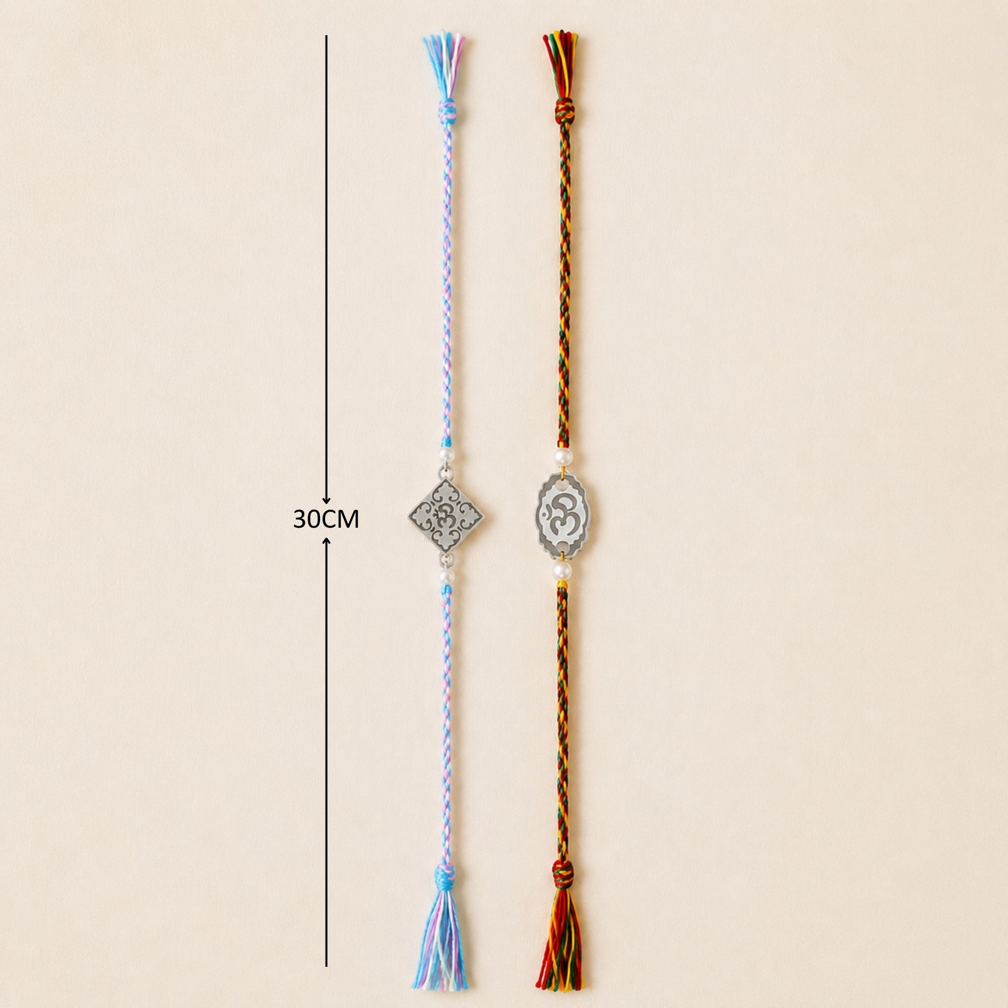 Two sterling silver Om and square filigree floral charm rakhis with pearl beads laid out vertically