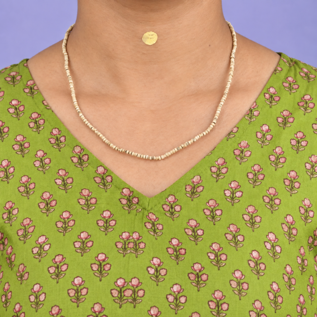Single-strand Tulsi kanthi mala with small disc-shaped wooden beads worn with a green floral kurta.