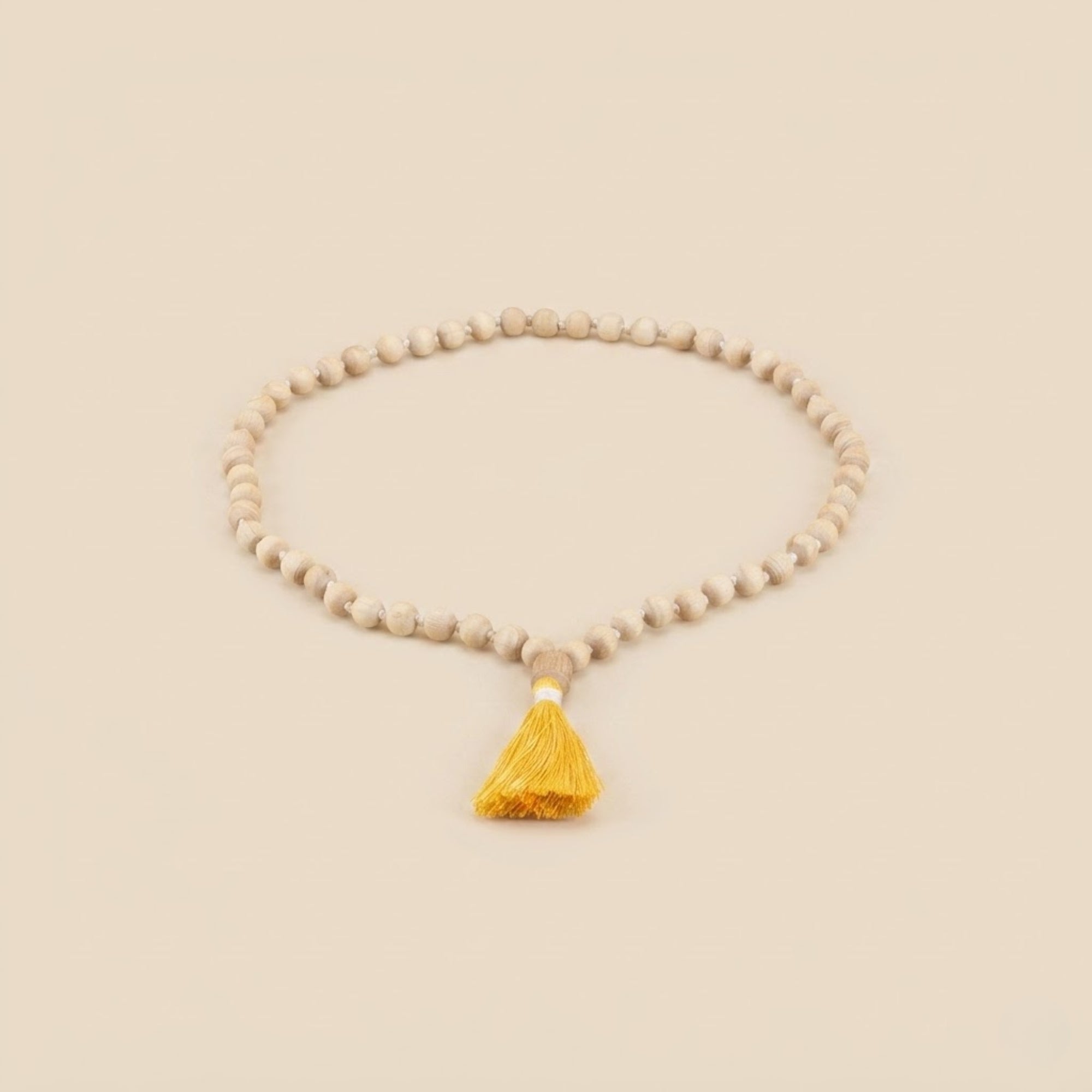 Close up of smooth round beads and a yellow tassel on a Tulsi japa mala