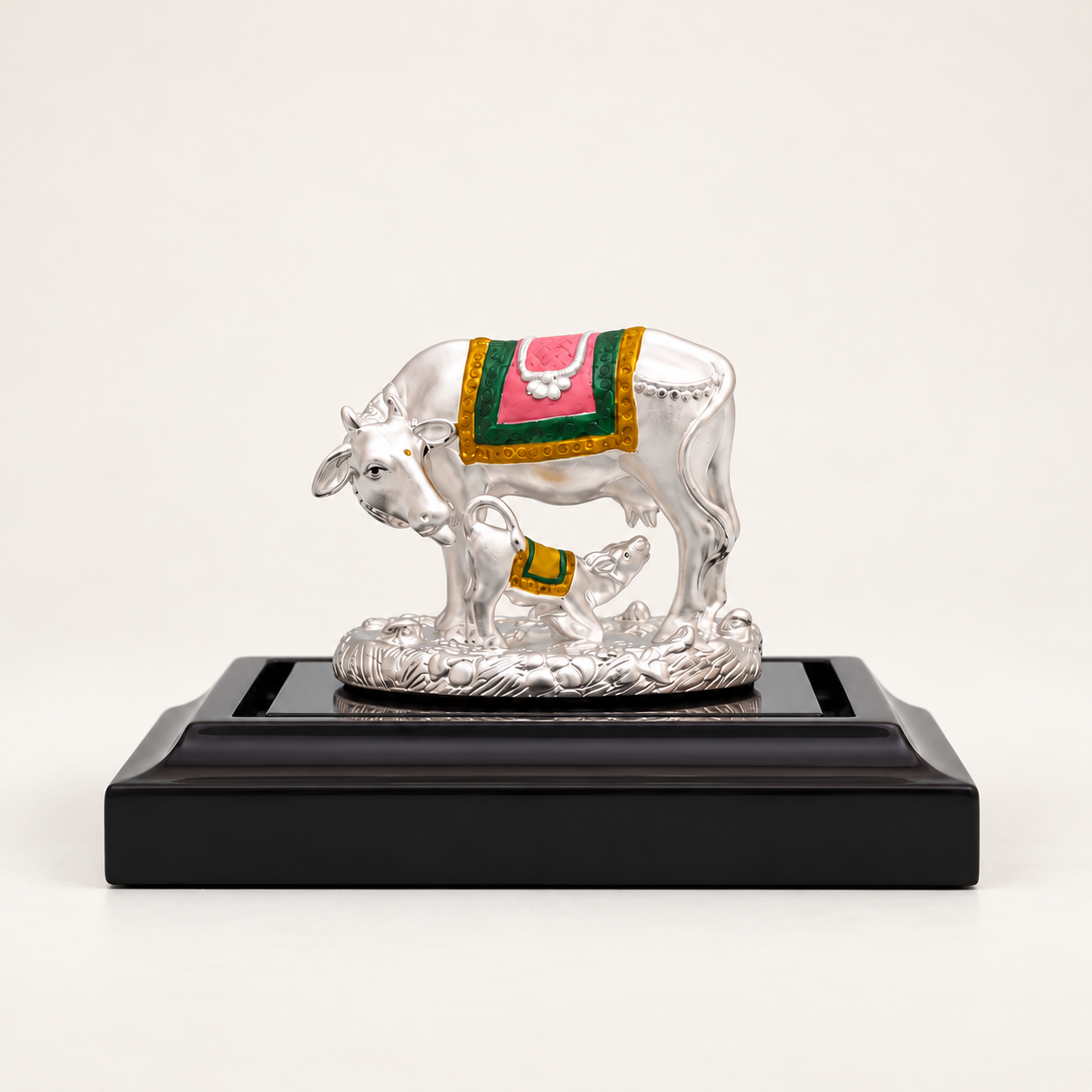 Sterling Silver cow and calf idol with pink, green and gold detailing on a black pedestal against an off-white background.
