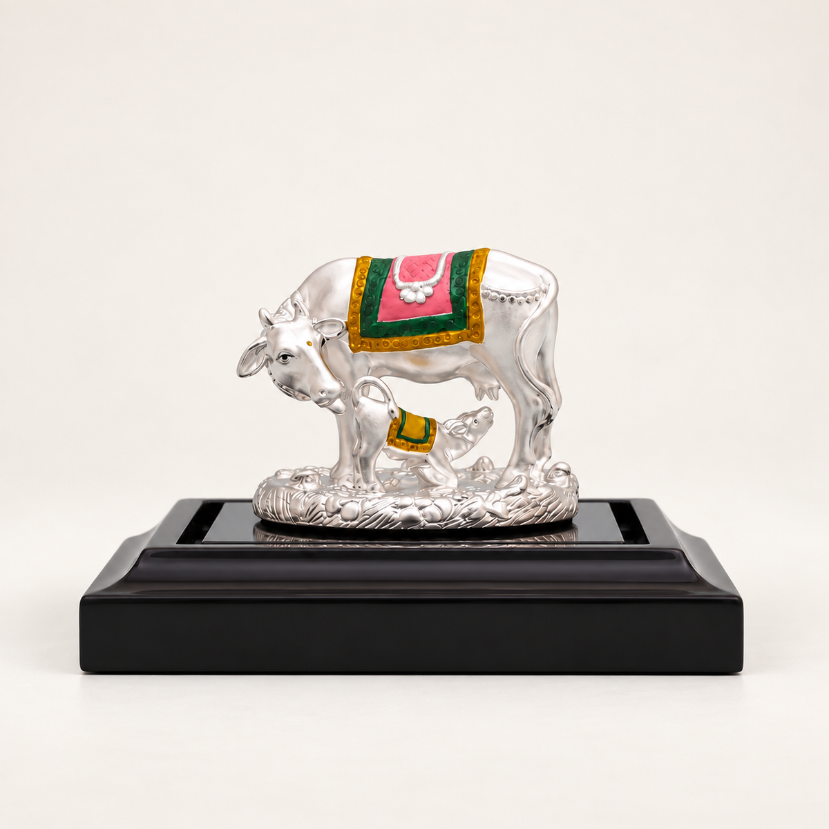 Sterling Silver cow and calf idol with pink, green and gold detailing on a black pedestal against an off-white background.