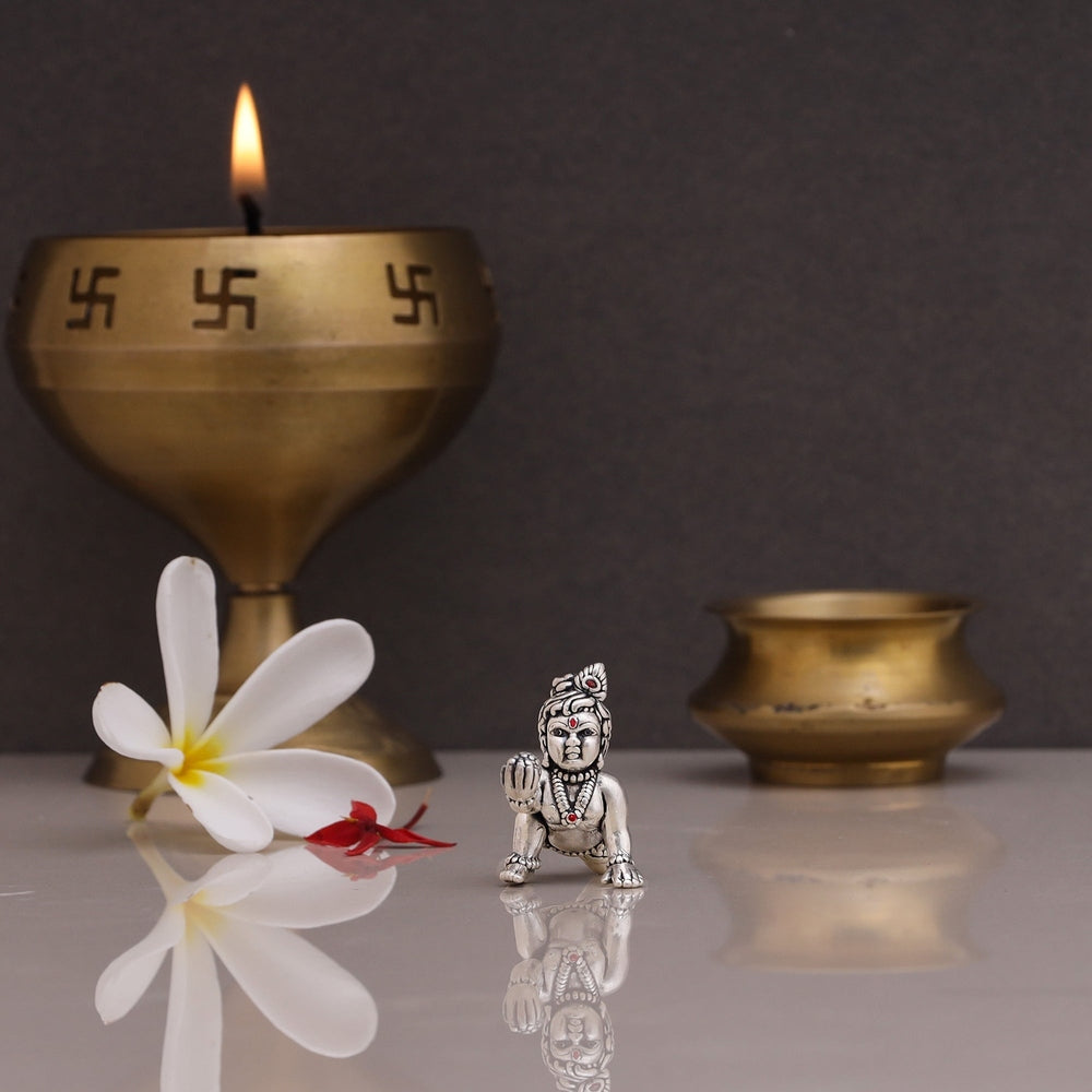 Sterling silver Laddu Gopal idol of beautiful deity displayed on a stand with a brass diya
