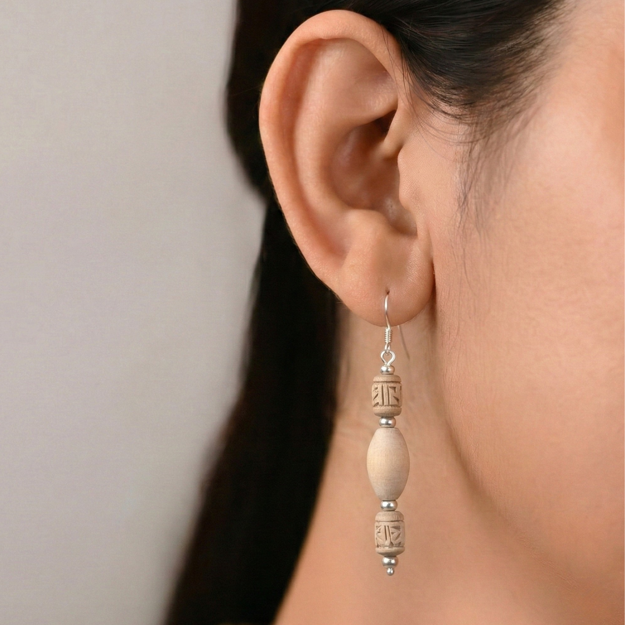 Woman wearing elegant sterling silver dangle earrings with authentic Tulsi wood beads