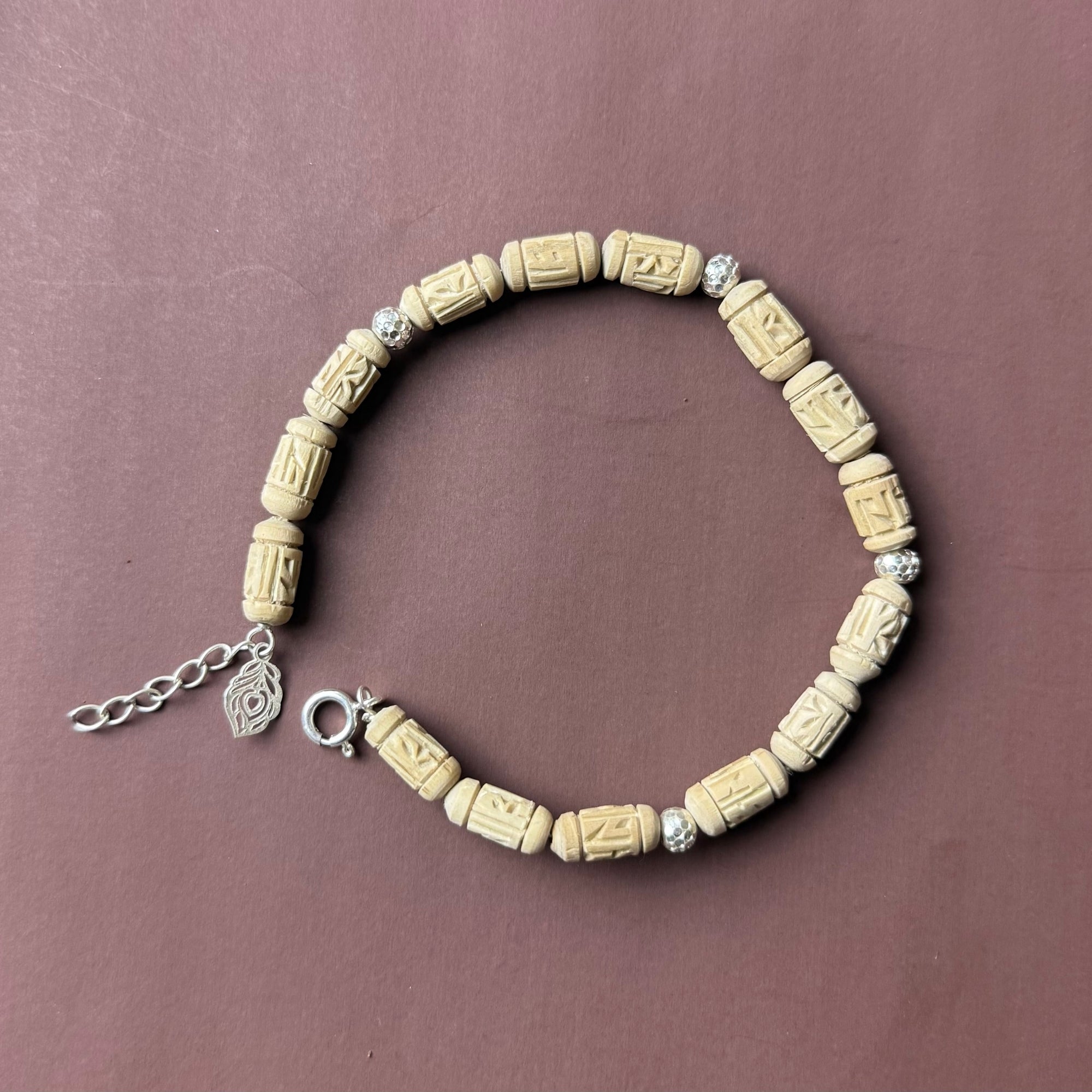 Close up flat lay of a sterling silver bracelet featuring authentic Tulsi wood beads and pearls