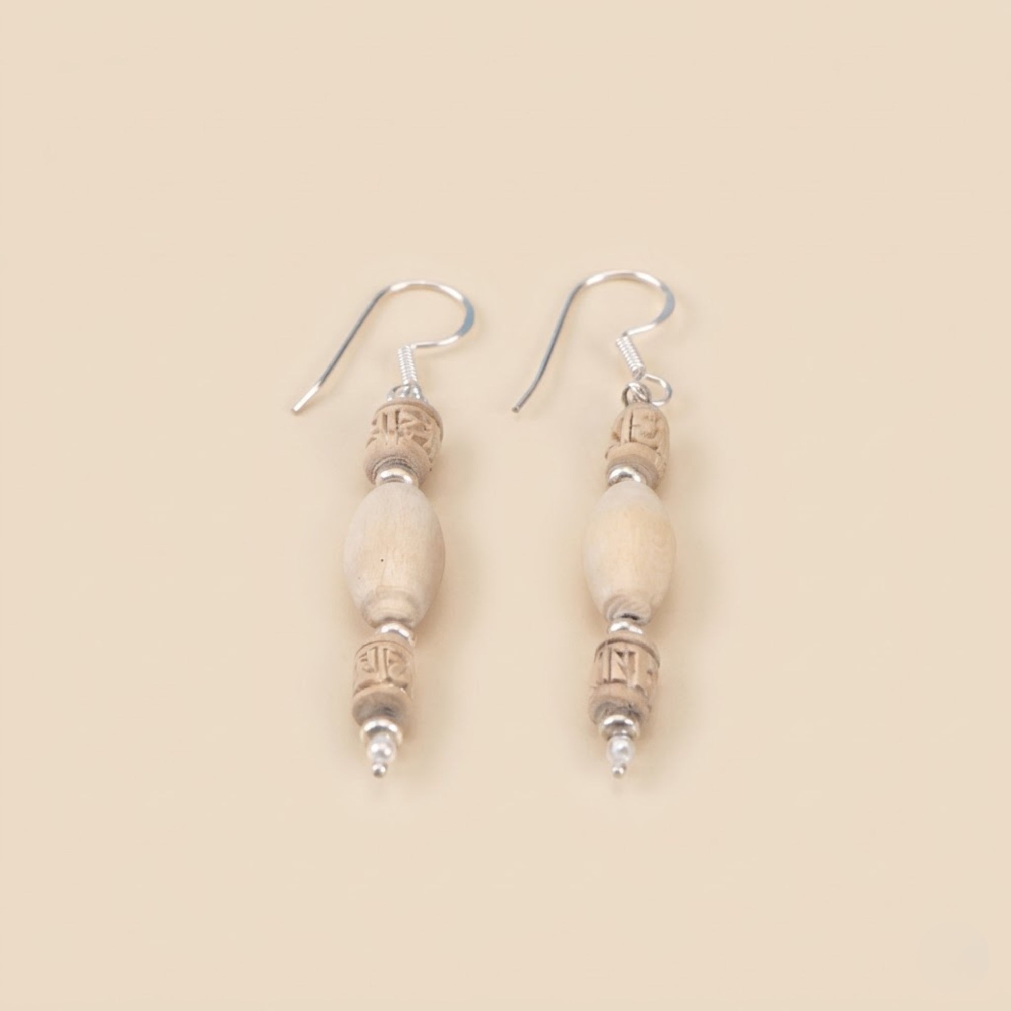 Close up flat lay of sterling silver dangle earrings featuring authentic Tulsi wood beads