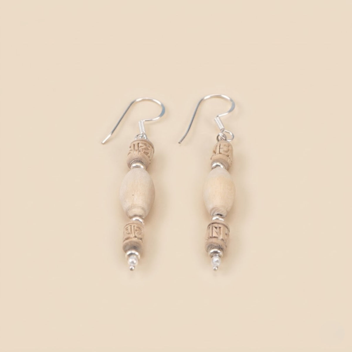 Close up flat lay of sterling silver dangle earrings featuring authentic Tulsi wood beads