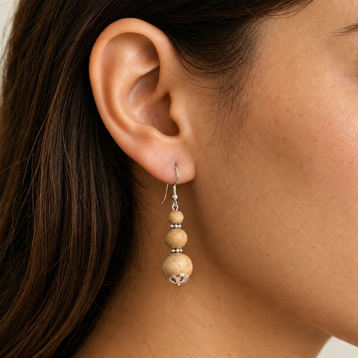 Tulsi drop earring with three graduated round wooden beads, silver-toned spacers and a decorative bottom cap.