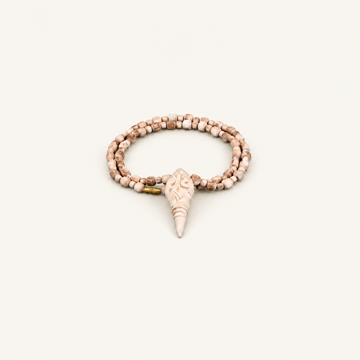 Tulsi bead mala with a carved conch-shaped pendant and gold-colored clasp on an off-white background.