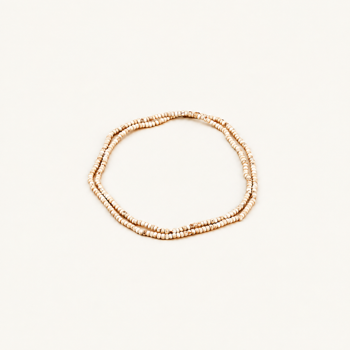 Off-white background par double loop mein rakhi chhote Tulsi beads ki mala.