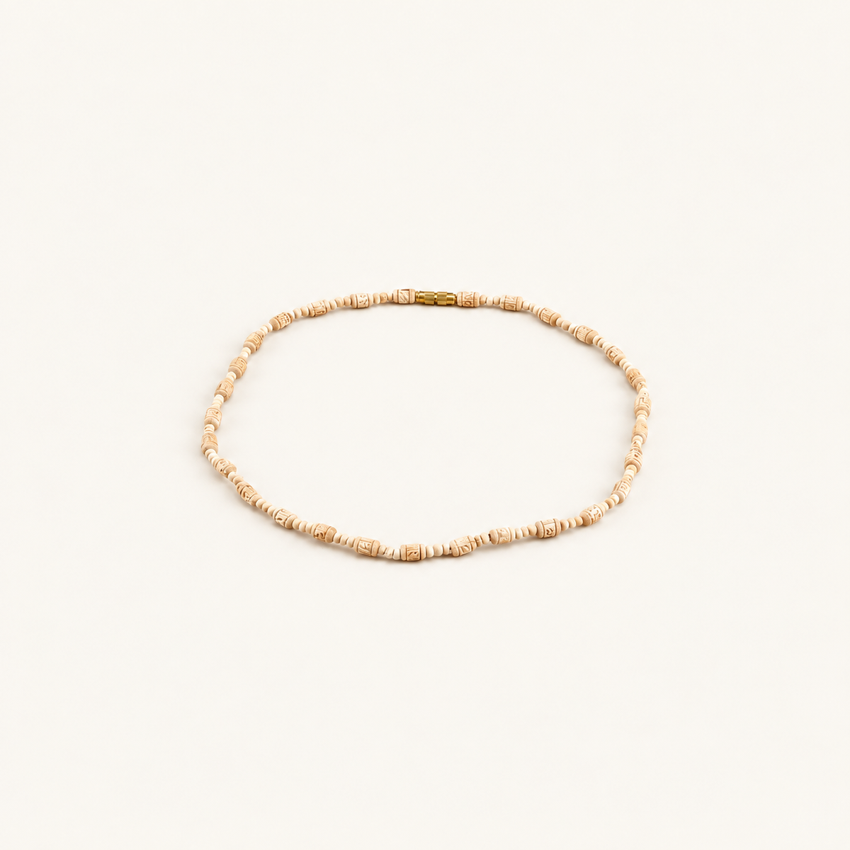 white-backgroundTulsi bead mala with carved beads and a gold clasp arranged on an off-white background.
