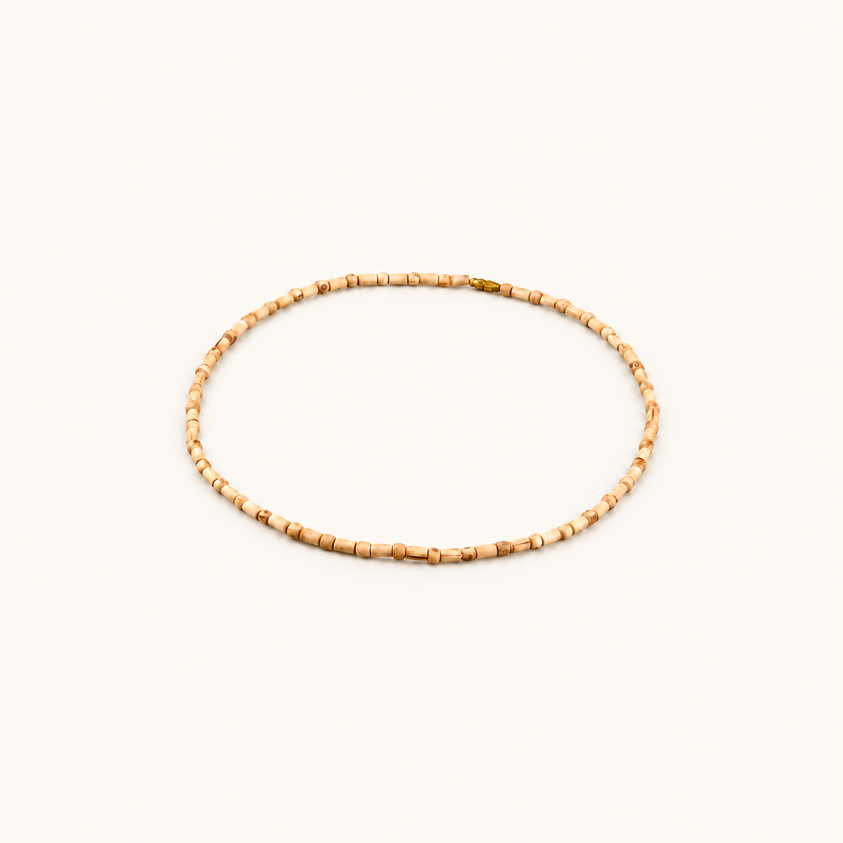Tulsi bead mala with cylindrical wooden beads and a metal clasp arranged on an off-white background.