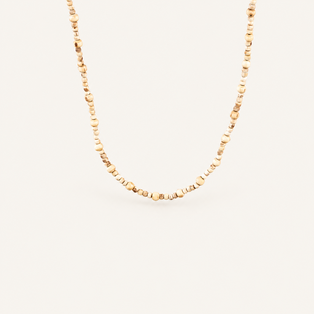 Close-up of a natural Tulsi bead mala with varied bead sizes on an off-white background.
