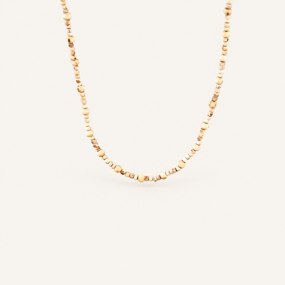 Close-up of a natural Tulsi bead mala with varied bead sizes on an off-white background.