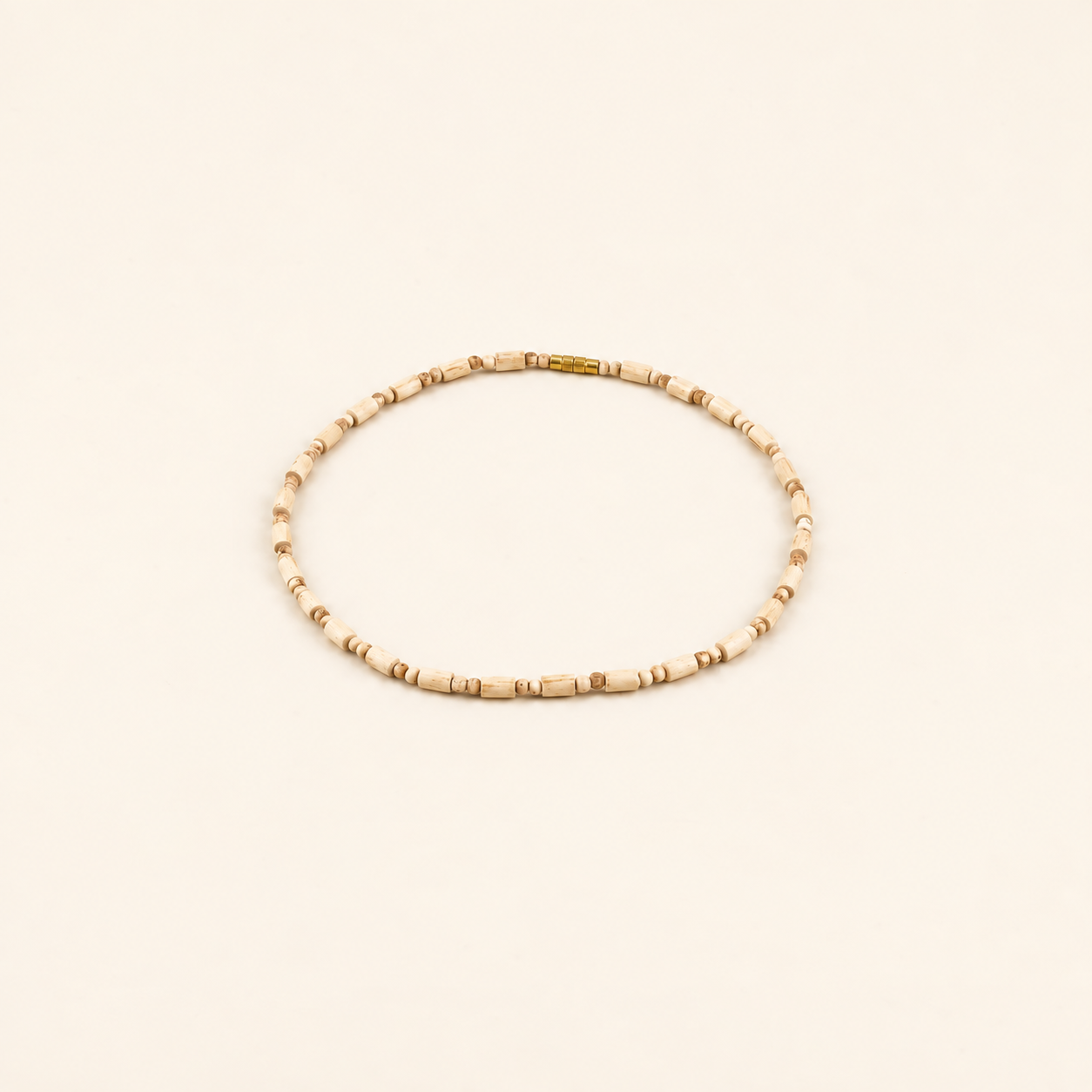 Tulsi bead mala with a gold clasp arranged in a circle on an off-white background.