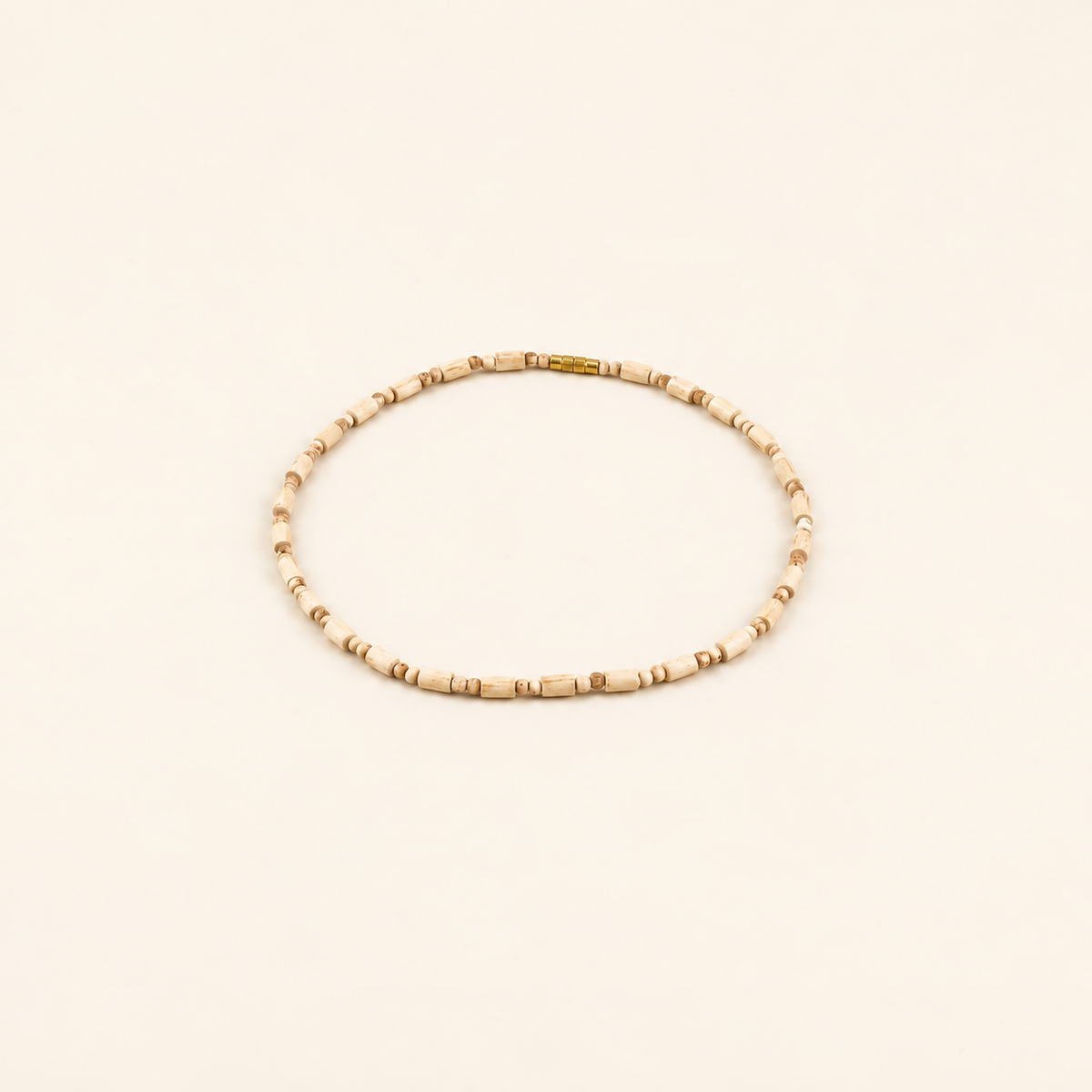Tulsi bead mala with a gold clasp arranged in a circle on an off-white background.