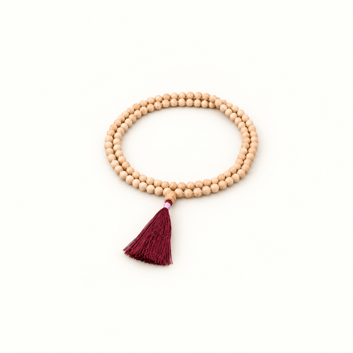 Tulsi japa mala with light wooden beads and a burgundy tassel arranged in two oval loops