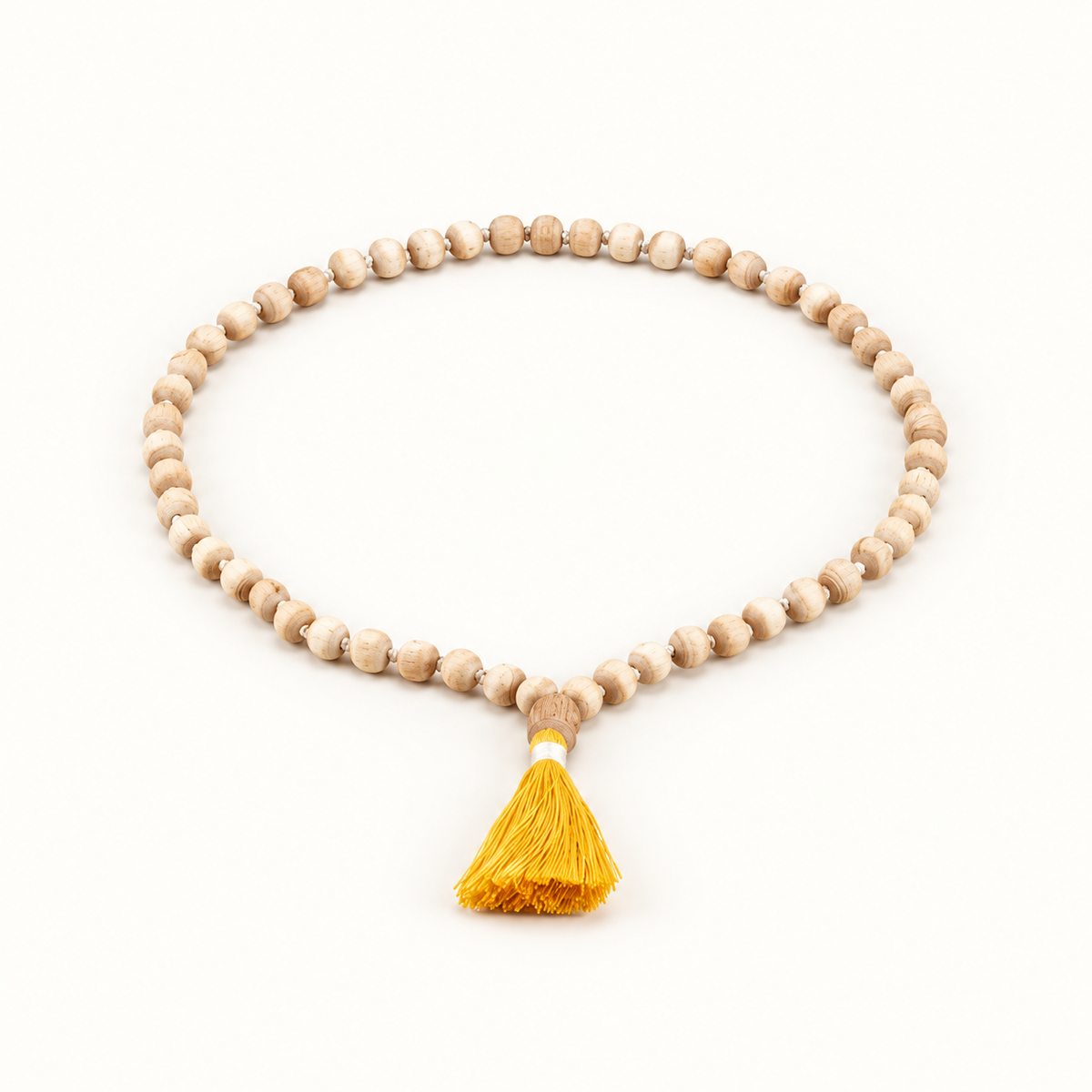 Light wooden Tulsi japa mala arranged in an oval with a yellow tassel on an off-white background.