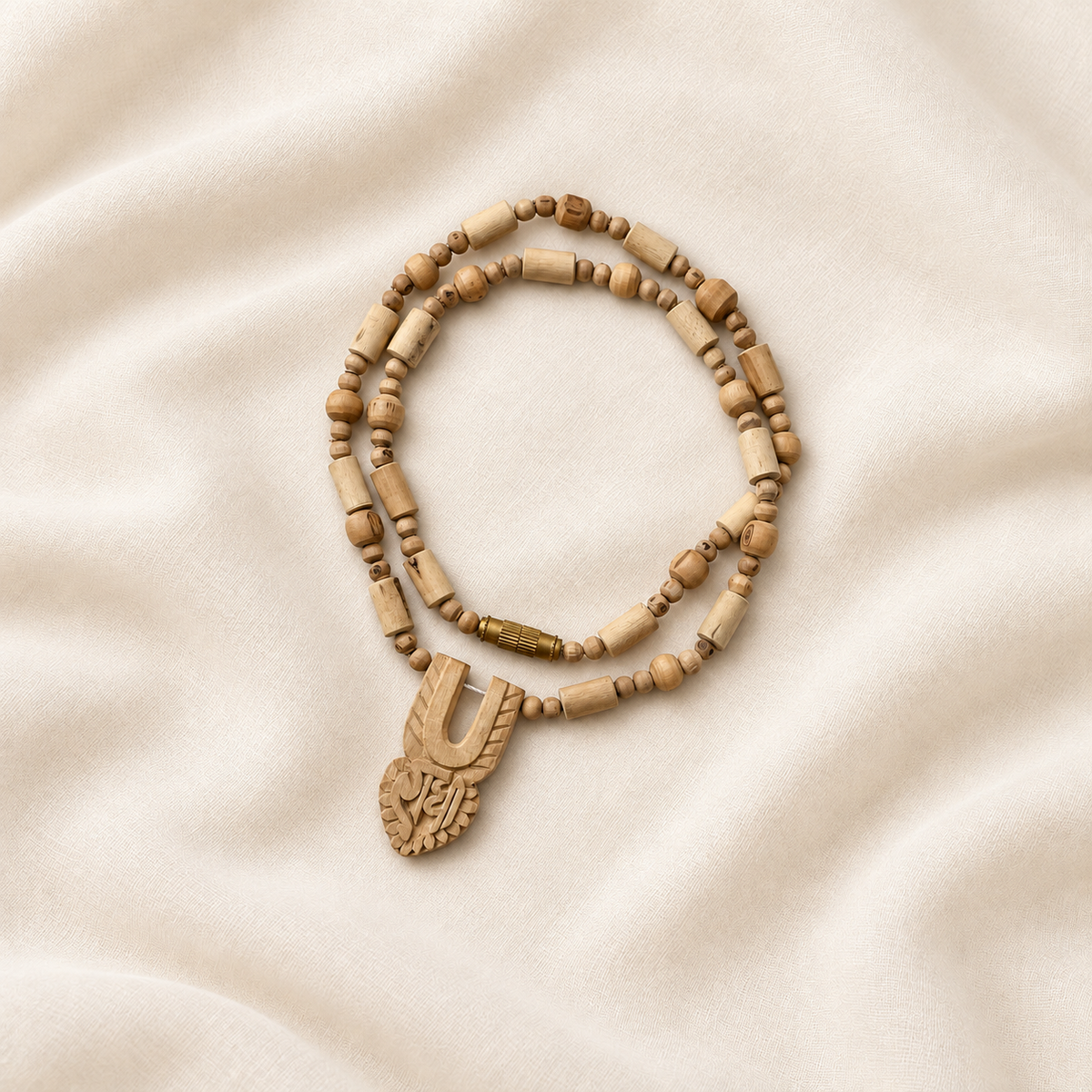 Handmade Tulsi wood Kanthi Mala with Radha carved pendant, natural wooden beads and golden clasp, displayed on cream fabric.