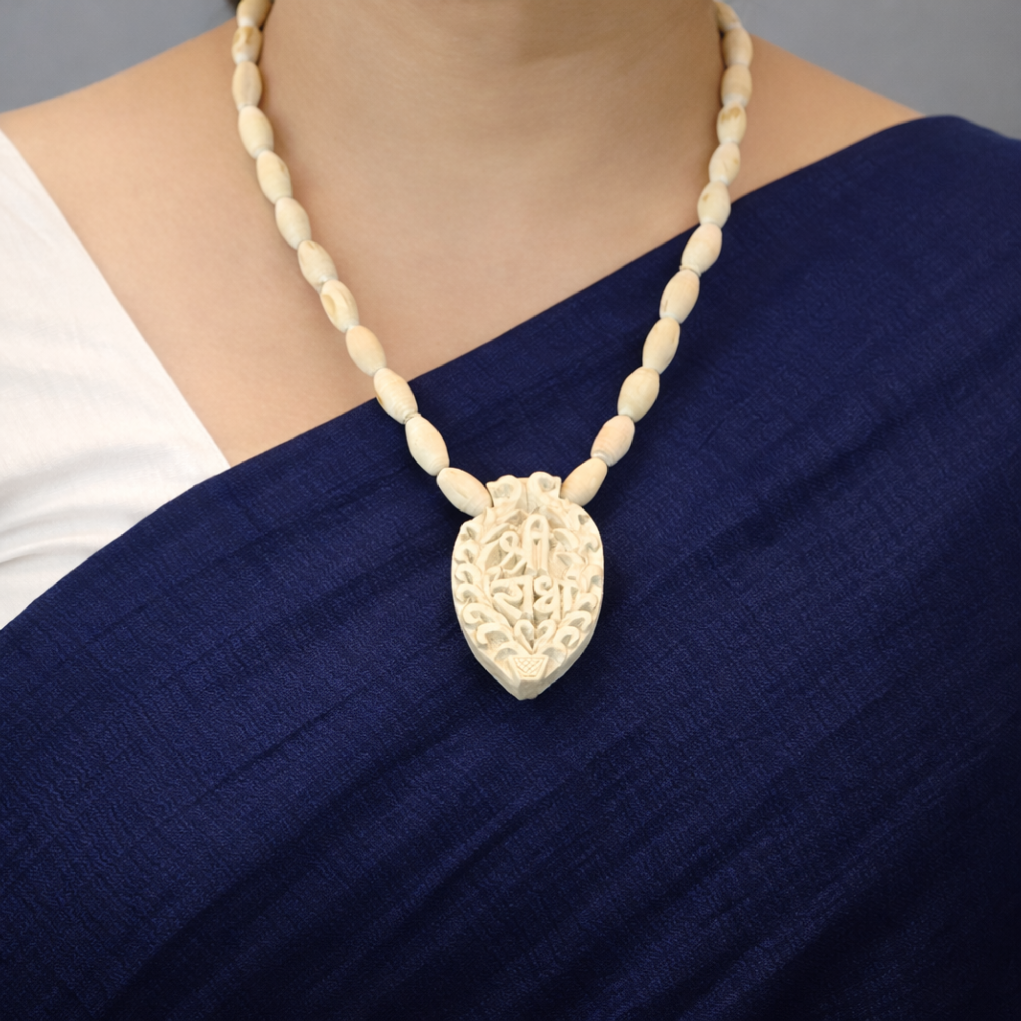 Woman wearing a traditional Tulsi Kanthi Mala necklace with a carved Shri Radha wood pendant