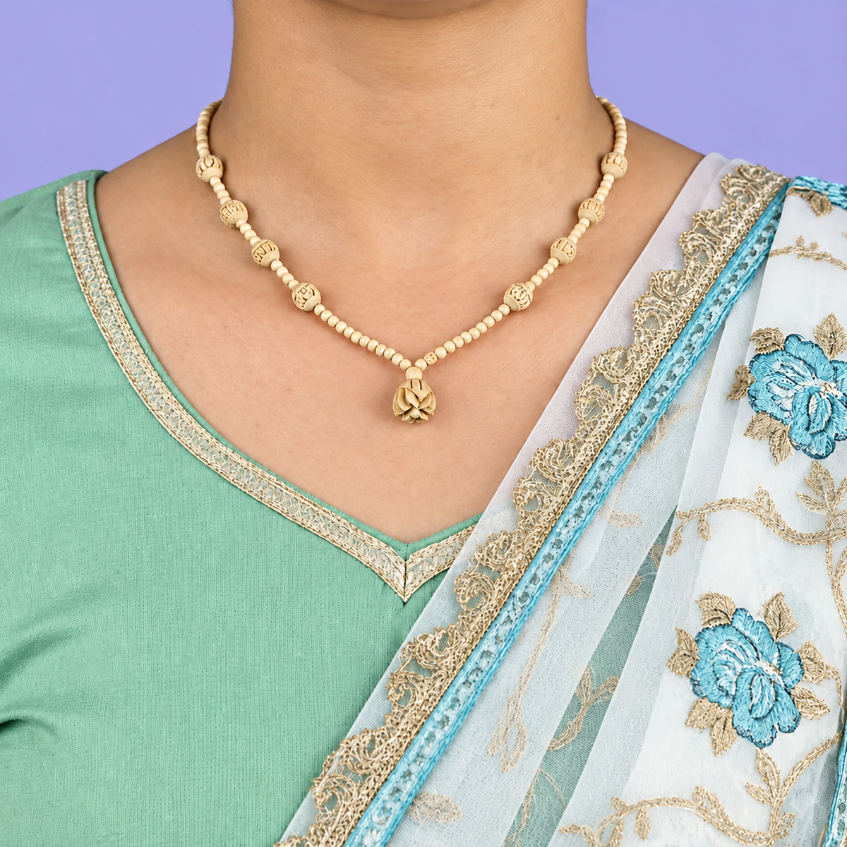 Tulsi mala with carved round beads and a flower pendant worn with a mint green outfit.