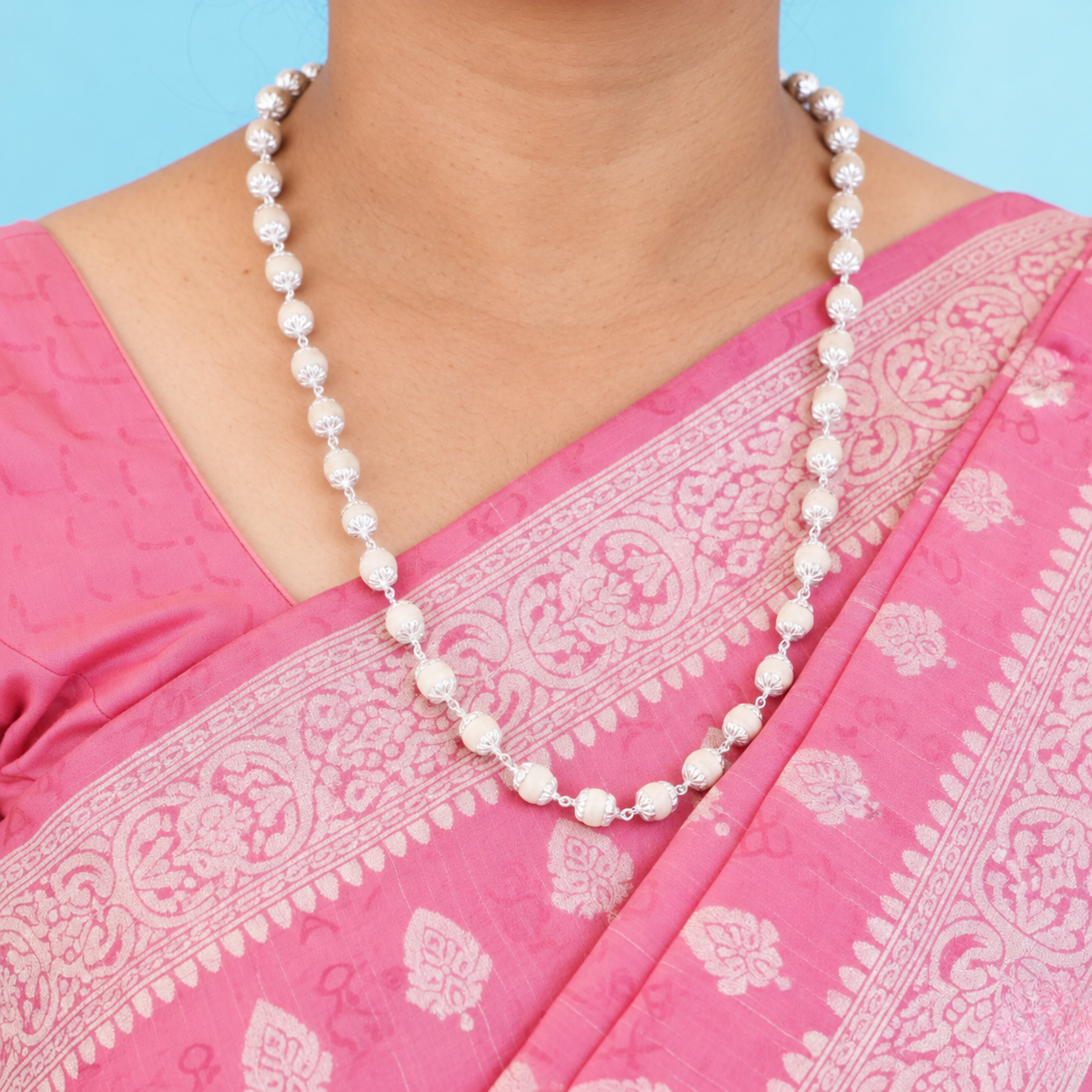 Tulsi mala with round wooden beads, floral silver-toned caps and chain links worn with a pink saree.