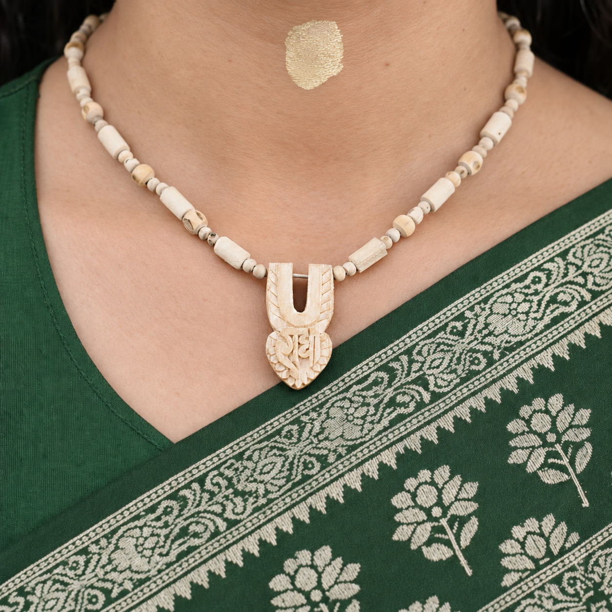 Tulsi mala with mixed wooden beads and a carved tilak and heart-shaped Radha pendant worn with a green saree.