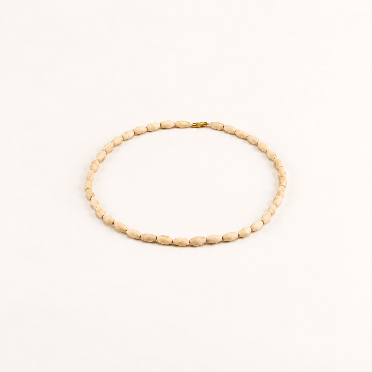Oval Tulsi bead mala with a gold clasp arranged on an off-white background.