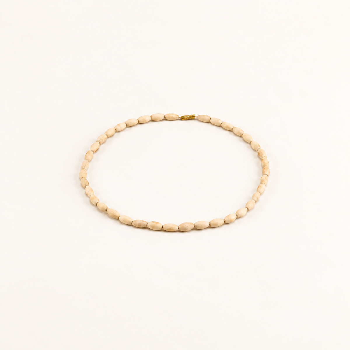 Oval Tulsi bead mala with a gold clasp arranged on an off-white background.