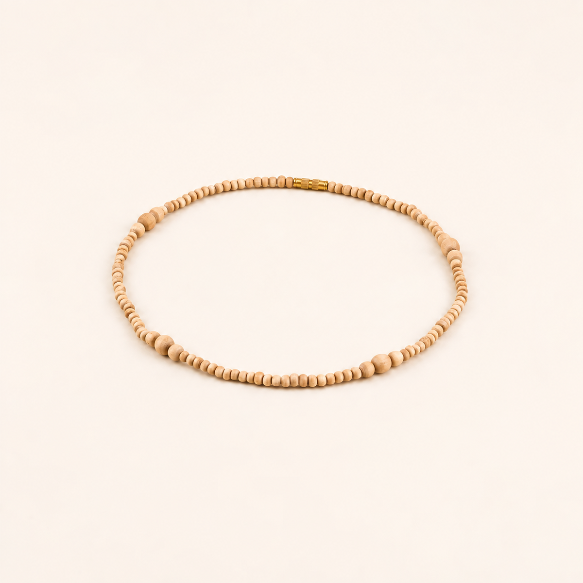 Tulsi wood bead mala arranged in an oval with a gold-tone clasp on an off-white background.