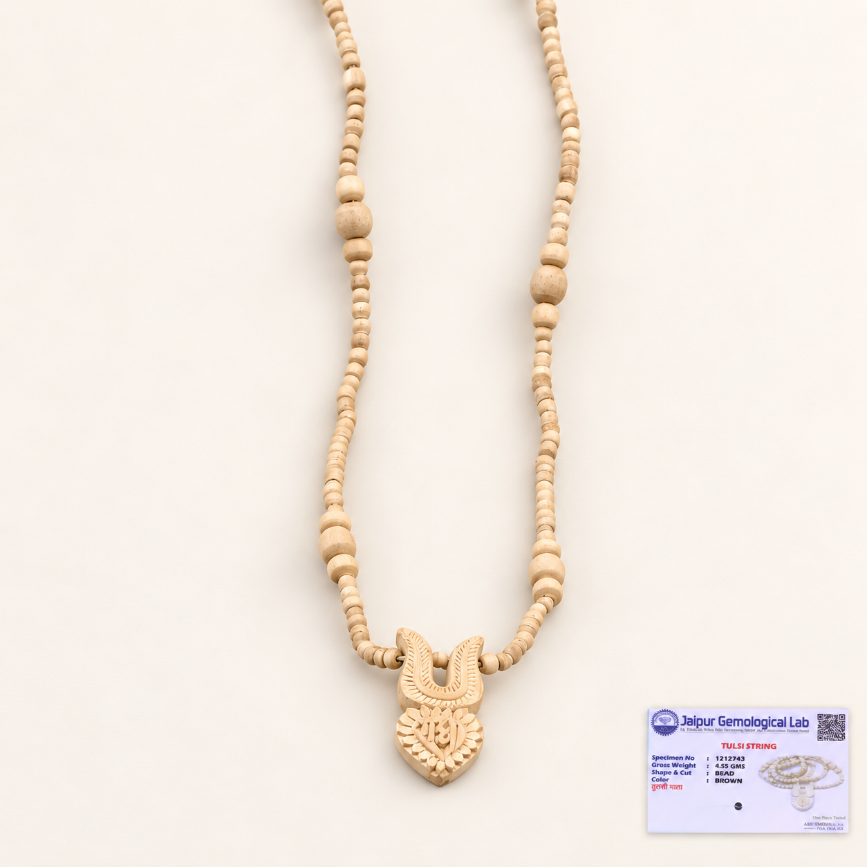 Tulsi wood bead mala with a carved pendant on an off-white background and a certificate at the bottom right.