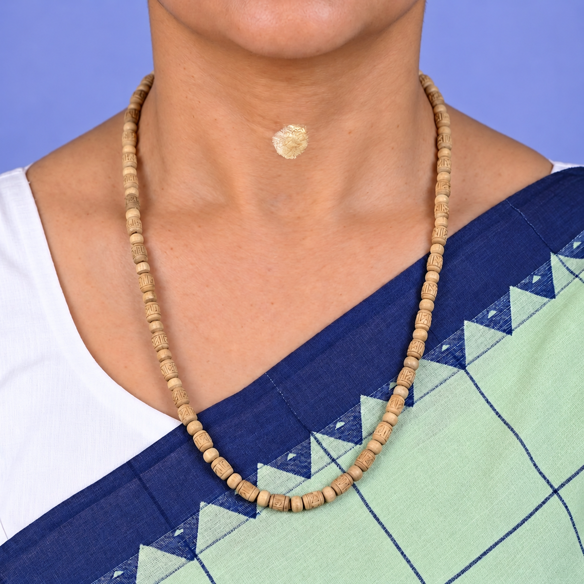Woman wearing a traditional Tulsi wood Kanthi Mala necklace with carved cylindrical beads and round wooden spacers, styled with a blue and green saree.