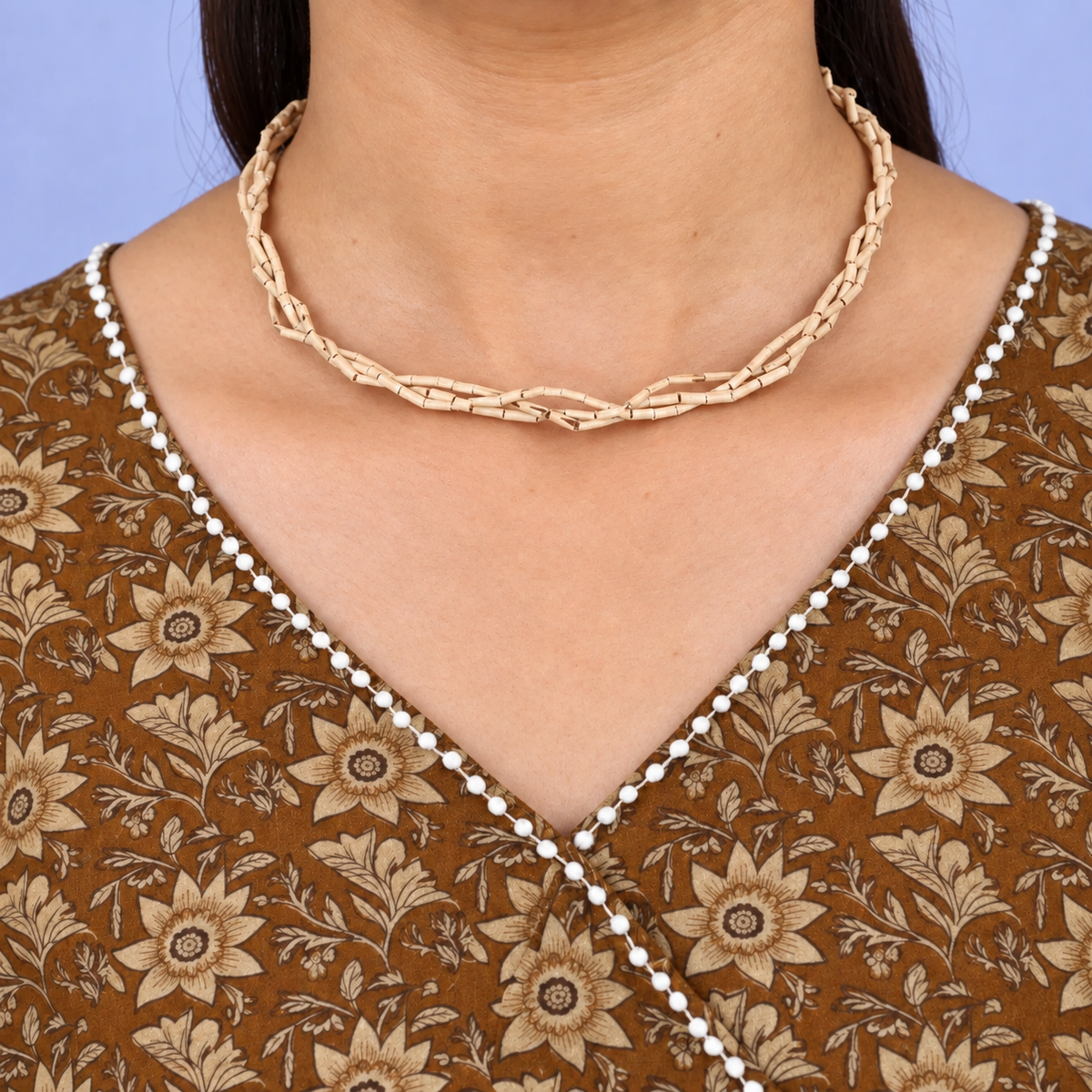 Twisted multistrand Tulsi kanthi mala with slender cylindrical wooden beads worn with a brown floral kurta.