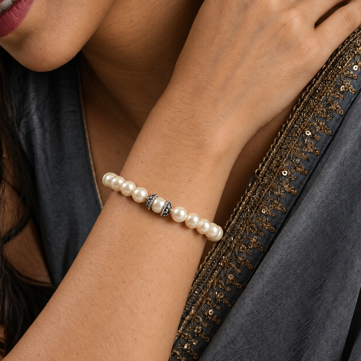Close-up of a woman wearing a white pearl bead bracelet with silver-toned accent spacers.